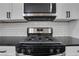 Close up of a kitchen with a black gas range, stainless steel microwave and white cabinets at 235 Holly Nw Rd, Atlanta, GA 30314