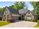 A beige stucco house with a large driveway and a two-car garage door and landscaping on a sunny day at 4569 Fountain Ne Dr, Marietta, GA 30067