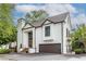 Elegant two-story home with white stucco exterior, brown trim, front-entry garage, and manicured landscaping at 1100 Parker Ne Pl, Atlanta, GA 30324