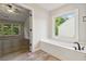 Bathroom featuring a soaking tub, tile floors, and views into the main bedroom at 1931 Abinger Way, Lawrenceville, GA 30043