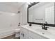 Bright bathroom featuring a double sink vanity, white cabinets, and a bathtub with tiled surround at 1931 Abinger Way, Lawrenceville, GA 30043