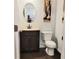 Compact bathroom featuring a vanity with a round mirror, a toilet, and a neutral color scheme at 110 Halibut Cir, Covington, GA 30016