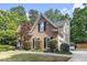 An eye-level shot of a well-manicured brick home with green lawn and trees, showcasing its exterior charm at 1235 Legend Run, Alpharetta, GA 30005