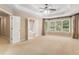 Spacious main bedroom showcasing neutral paint, carpet, a ceiling fan, large windows, and an ensuite bath with a soaking tub at 1235 Legend Run, Alpharetta, GA 30005