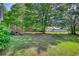 Grassy backyard with mature trees and a wooden deck providing an inviting outdoor space for relaxation at 65 Ashland Farm Rd, Oxford, GA 30054