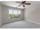 Sunlit bedroom featuring three windows overlooking mature trees, with neutral carpet and ceiling fan at 1077 Shady Valley Ne Pl, Atlanta, GA 30324