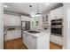 Bright kitchen features stainless appliances, center island with cooktop and modern pendant lighting at 1077 Shady Valley Ne Pl, Atlanta, GA 30324