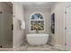 Relaxing soaking tub beneath an arched window complements the gorgeous shower at 1077 Shady Valley Ne Pl, Atlanta, GA 30324