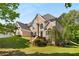 Stately brick home with lush front lawn, mature trees, and elegant architectural details on a sunny day at 679 Gold Valley Pass, Canton, GA 30114