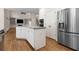 Open kitchen featuring a granite island, stainless steel refrigerator, double ovens, and hardwood floors at 679 Gold Valley Pass, Canton, GA 30114