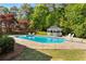 Sparkling swimming pool with a gazebo, surrounded by lush greenery and a stone patio, perfect for summer fun at 679 Gold Valley Pass, Canton, GA 30114