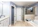 Well-lit bathroom featuring a bathtub with shower, tiled flooring, and a white cabinet at 1114 Ivey Chase Pl, Dacula, GA 30019