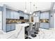 Modern kitchen with a large island, pendant lighting, marble floors, and light blue cabinetry at 1114 Ivey Chase Pl, Dacula, GA 30019