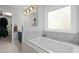 Bright bathroom with a marble tiled soaking tub and a view of the large window at 2297 Ironwood Hill Ct, Dacula, GA 30019