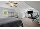 A large bedroom with desk, shelves, cabinets, TV, ceiling fan, and a comfortable chair at 2297 Ironwood Hill Ct, Dacula, GA 30019