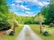 Long gravel driveway, surrounded by lush greenery and rustic decorations, leads to the property at 8032 Banks Mill Rd, Douglasville, GA 30135
