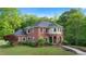 Charming red brick two-story home with lush landscaping, a manicured lawn, and an inviting entrance at 8032 Banks Mill Rd, Douglasville, GA 30135
