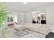 Bright living room featuring a plush white sectional, glass coffee table, and open access to kitchen and outdoor living space at 2180 Dunwoody Heritage Dr, Atlanta, GA 30350