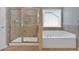 Primary bathroom showcasing a soaking tub, walk-in shower, and natural light streaming through the window at 221 Hampton Station Blvd, Canton, GA 30115
