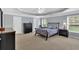 Spacious bedroom with a tray ceiling, neutral color scheme, and large windows overlooking greenery at 221 Hampton Station Blvd, Canton, GA 30115