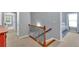Upper hallway featuring a wooden railing, neutral walls, and access to multiple rooms at 221 Hampton Station Blvd, Canton, GA 30115