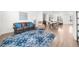 Open-concept living space features hardwood floors, leather sofa, a blue rug, and plenty of natural light at 3239 Bartee Walk, Suwanee, GA 30024