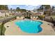 An aerial view showcases the swimming pool, its surrounding patio, tables, and sun loungers, perfect for summer relaxation at 3239 Bartee Walk, Suwanee, GA 30024