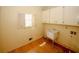 Laundry room equipped with a sink, storage cabinets, a window, and wood flooring at 110 Vistacrest Way, Roswell, GA 30075
