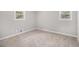 A cozy bedroom with neutral walls, carpeted floors, and bright natural light from the windows at 7248 Banks Mill Rd, Douglasville, GA 30135