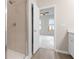 Shower with tan tiled walls and a glass door; open view to a bedroom with ceiling fan at 18 Black Gum Ln # 53, Auburn, GA 30011