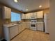 Bright and clean kitchen with white cabinets, tile flooring, and a complete set of appliances at 606 Windcroft Nw Cir, Acworth, GA 30101