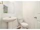 Cozy half bathroom features a pedestal sink, toilet and door at 7454 Silver Arrow Se Trl, Austell, GA 30168