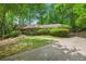 Charming single-story home with lush landscaping, mature trees, and a brick wall at 12080 Mountain Laurel Dr, Roswell, GA 30075