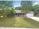 Charming single-story home with a brick facade, manicured lawn and attached two-car garage and front porch at 2012 Elm Grove Ln, Hampton, GA 30228