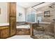 Elegant bathroom with a modern glass shower, soaking tub, and decorative wood paneling at 318 Dogwood Trce, Mcdonough, GA 30252