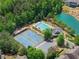 Aerial view features the community pool, tennis courts, clubhouse, and tranquil pond surrounded by lush trees at 4190 Madison Dr, Cumming, GA 30040