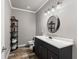 Bathroom featuring an oval mirror above a single vanity, wood plank flooring, and ample lighting at 4190 Madison Dr, Cumming, GA 30040