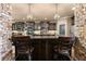 Kitchen island featuring granite countertops, dark wood cabinets, stone columns, and chandelier lighting at 4190 Madison Dr, Cumming, GA 30040