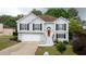 Charming two-story home featuring an attached garage, neatly landscaped yard and a bright orange front door at 440 Hickory Glen Sw Ln, Atlanta, GA 30311