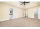Spacious main bedroom featuring plush carpeting, a tray ceiling with a fan, and entrances to the bathroom and closet at 440 Hickory Glen Sw Ln, Atlanta, GA 30311