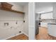 Laundry room with built-in shelf, adjacent to the kitchen with wood-look flooring at 6292 Field Glen Rd, Stone Mountain, GA 30087
