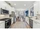 Open-concept kitchen featuring white cabinets, stainless appliances, quartz countertops, and an adjacent dining area at 409 Norton Xing, Woodstock, GA 30188