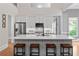 Bright kitchen features a large island with marble countertops, wood stools, and stainless steel appliances at 1440 Water View Ln, Suwanee, GA 30024