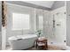 Bright main bathroom featuring marble tile, soaking tub, and glass enclosed shower at 1440 Water View Ln, Suwanee, GA 30024