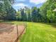 Large backyard with lush green grass, mature trees, and a fenced dog run at 527 Tomahawk Trl, Woodstock, GA 30188