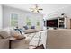 Open living room with a decorative sign, large windows, a ceiling fan, and a TV offers ample natural light at 10200 Windalier Way, Roswell, GA 30076