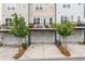 Townhome back view showcasing balconies, garages, and tasteful landscaping for outdoor living at 10200 Windalier Way, Roswell, GA 30076