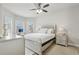 Charming bedroom with a decorative bed frame, a ceiling fan, and sunlit windows overlooking the neighborhood at 5180 Mirror Lake Dr, Cumming, GA 30028