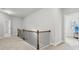 Upstairs hallway with wood railing and view to a bedroom with large windows at 5180 Mirror Lake Dr, Cumming, GA 30028