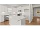 Bright kitchen boasts white cabinets, stainless steel appliances, island, and wood flooring at 488 Village Ln, Fairburn, GA 30213